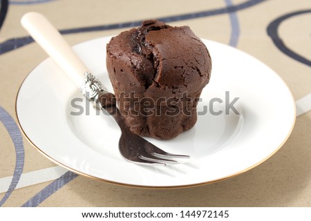 Small french chocolate cake made in muffin mold on the white plate with fork