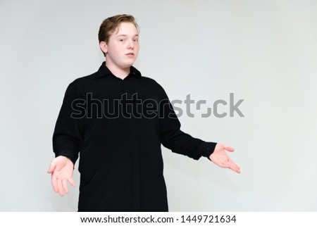 Portrait to the waist on a white background of a handsome young man in a black shirt. stands directly in front of the camera in different poses, talking, showing emotions, showing hands.