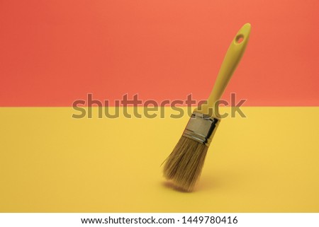 New paint brush on a coral orange and yellow background.