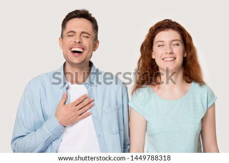 Sincere young family couple laughing portrait, handsome man and attractive woman laughing at joke, having fun together, happy to hear perfect news, isolated on grey white studio background.
