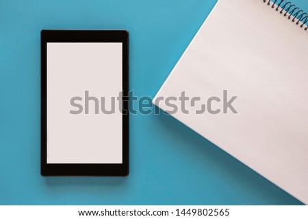 Computer tablet and sketch pad on a blue background. Top view. Copy space. 