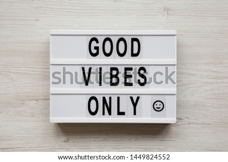 'Good vibes only' words on a modern board on a white wooden surface, top view. From above, overhead, flat lay. 