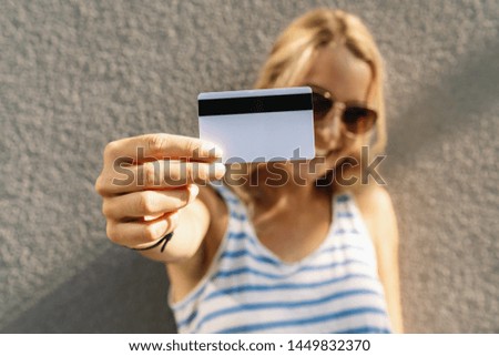 Portrait of a pretty young woman dressed in sweater holding credit card at her face. copyspace for your individual text. 