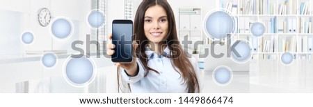 Smiling woman shows smartphone with empty icons isolated on interior office background