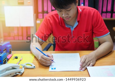 Man filling application form in the office,  selective focused picture of an officer working or preparing document in a work place. Business or education concept photo of a young lad doing his jobs
