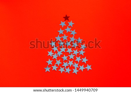 Stars shine in the form Christmas tree silhouette on red background. Minimal composition with copy space, flat lay, top view. Creative concept