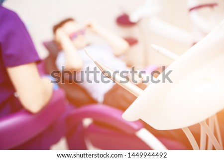 Blurred dental office. Tools are in the foreground. The boy with goggles in the dental chair