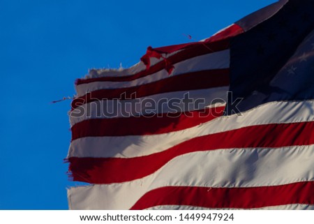 Detail of frayed old flag of the United States of America against a blue sky
