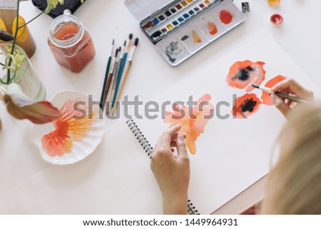 Overhead view female designer making abstract watercolor sketches. Stylish artistic workspace with professional tools.