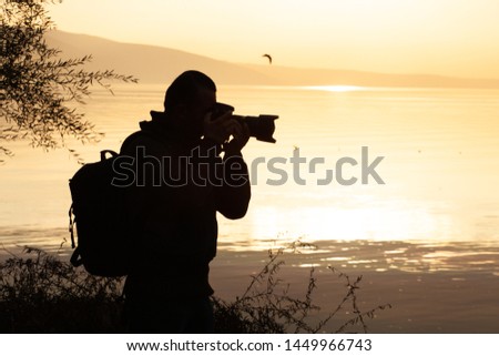 silhouette of photographer, taking photo at sunset beside the lake
