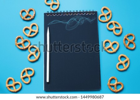 Notepad with black sheets on a blue background with cookies, space for entries
