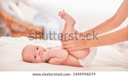 gymnastics baby. woman doing exercises with baby for its development. massage a small newborn baby. love, a caring mother helps the bench to relieve the stress of colic belly,difficulty of gas removal Royalty-Free Stock Photo #1449996074