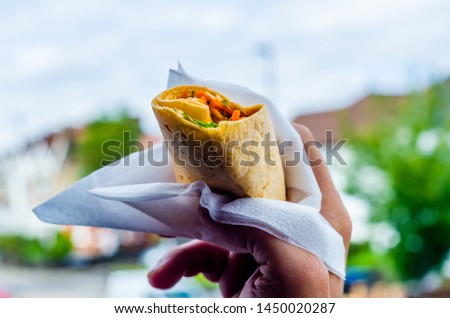Chicken breast with piri piri sauce and lettuce in a chili tortilla wrap in the hand, tasty food