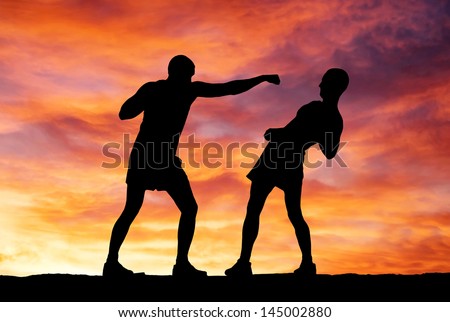Silhouettes of two fighters on sunset background