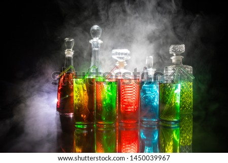 Multicolored glasses filled with alcoholic drinks, with splases of ice cubes falling inside, standing on the mirror surface. Black background. Conceptual, celebrated, commercial design. Closeup.