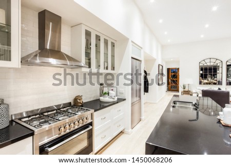 A stylish modular kitchen with a refrigerator next to it and a kitchen counter opposite the shelves and the stove. Royalty-Free Stock Photo #1450068206