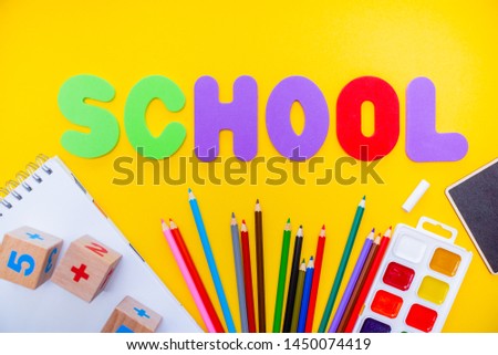  school supplies colorfull flatlay. Pencils notepad numbs a b c alphabet waterolors. Horizontal top view several objects above.
