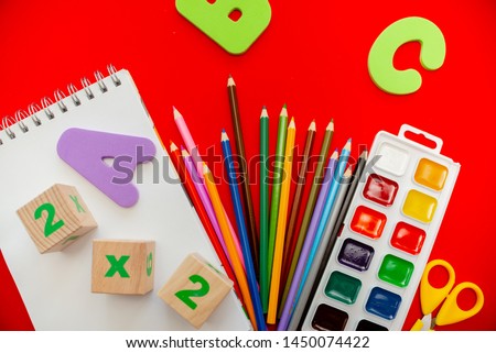  school supplies colorfull flatlay. Pencils notepad numbs a b c alphabet waterolors. Horizontal top view several objects above.