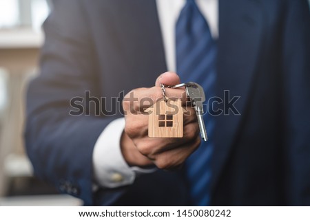 Close up view realtor broker holding home keychain in his hand. Royalty-Free Stock Photo #1450080242