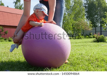 Mom helps the baby to do exercises on the fitness ball