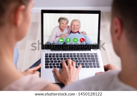 Close-up Of An Couple Video Conferencing With Their Happy Parents On Laptop Royalty-Free Stock Photo #1450128122
