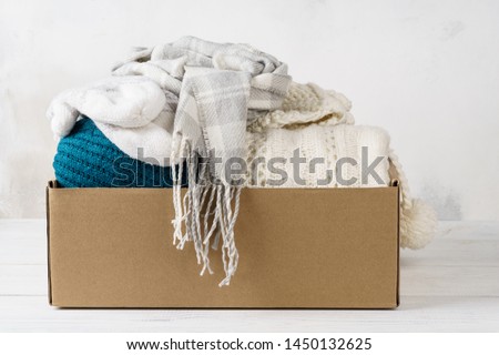 Winter clothes in a cardboard box. Seasonal clothing for shipping or donation.
