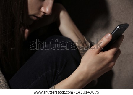 Woman using smartphone in dark room, closeup. Loneliness concept