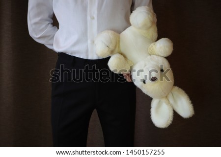 young man in a white shirt and black pants holding a toy hare. A man with a big toy rabbit. a man in love. a gift for the woman I love