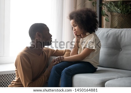 Loving african American father talk with upset preschooler daughter helping with problem, caring black young dad speak with sad girl child holding caressing hand, show support and understanding Royalty-Free Stock Photo #1450164881