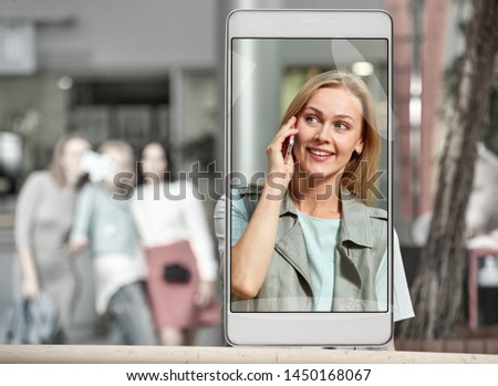Smartphone displaying photo of young woman talking on phone at mall