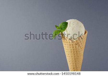 Classic white creamy ice cream in crisp waffle cone decorated green mint leaf on grey background, closeup, details, top.