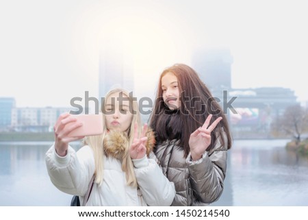 Two young teenage friends posing for photo selfie in a city park on a day early sunny morning