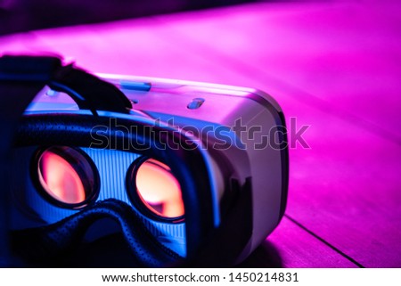 3d 360 vr headset glasses goggles lenses in futuristic purple neon light on table, virtual augmented ar reality innovative party experience digital mobile technology background concept, close up view