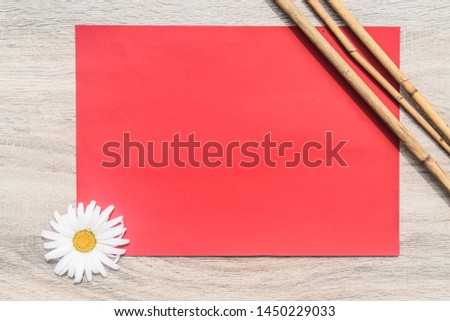 Red paper, daisy flower and branches on wooden background. Digital mock-up stock photo in aesthetic minimal style with free empty copy space for text or artwork design