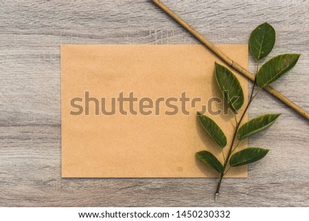 Cardboard piece with leaves and branch on wooden background. Digital mock-up stock photo in aesthetic minimal style with free empty copy space for text or artwork design
