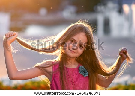 Portrait of a beautiful girl at sunset, a child in the sun, the sun in the girl's hair, child portrait close-up