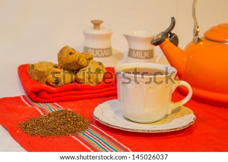 Rooibos tea and rusks An arrangement of Rooibos tea, rusks, tea leaves with a sugar jar, milk jug and orange kettle.