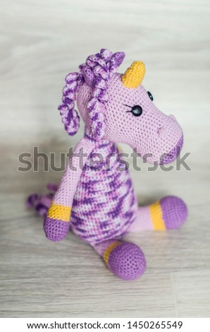 Crocheted unicorn lilac of melange threads are yellow elements. A nice toy handmade.