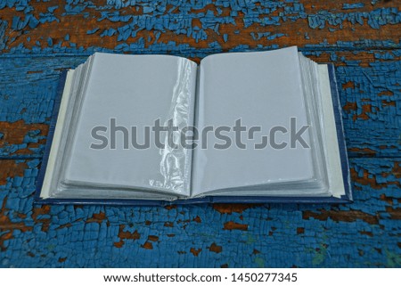 one open plastic album with white pages on a blue shabby table