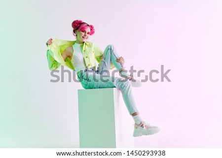 woman with pink hair sits on a neon fashion cube