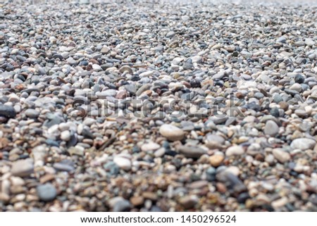 The texture of the pebbly beach. Background of small pebbles on the beach. Blurry background. A picture with an open aperture.