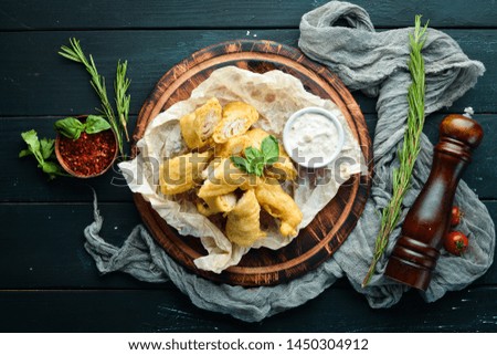 Fried fish fillet with sauce. On a wooden board. On a wooden background. Top view. Free space for your text.