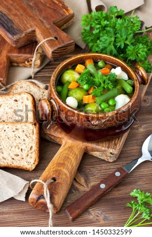 Vegetable soup in ceramic bowl on wooden table, selective focus with shallow depth of field