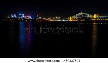 Night view of the iconic Sydney Harbour Bridge and the North Sydney suburb (left), from the Balmain East Wharf ferry terminal. Features plenty of colorful lighting with reflections from the water.