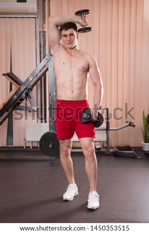Young man flexing muscles with barbell in gym. Close-up.