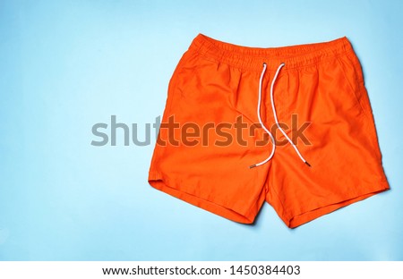 Stylish male swim trunks on color background, top view with space for text. Beach object Royalty-Free Stock Photo #1450384403