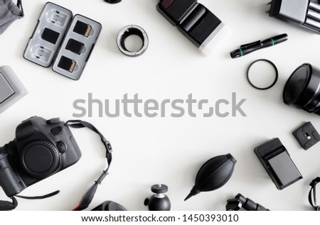 top view of work space photographer with digital camera, flash, cleaning kit, memory card, tripod and camera accessory on white table background