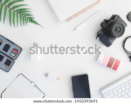 top view of Designer work space with notebook, smartphone, colour swatches book and keyboard on white background.