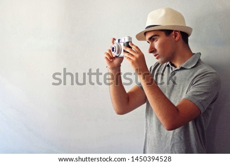 Man dressed in gray and in a hat taking some pictures.
