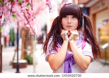 Beautiful Asian model in Japanese student uniform with cherry blossom flower  Royalty-Free Stock Photo #1450420730